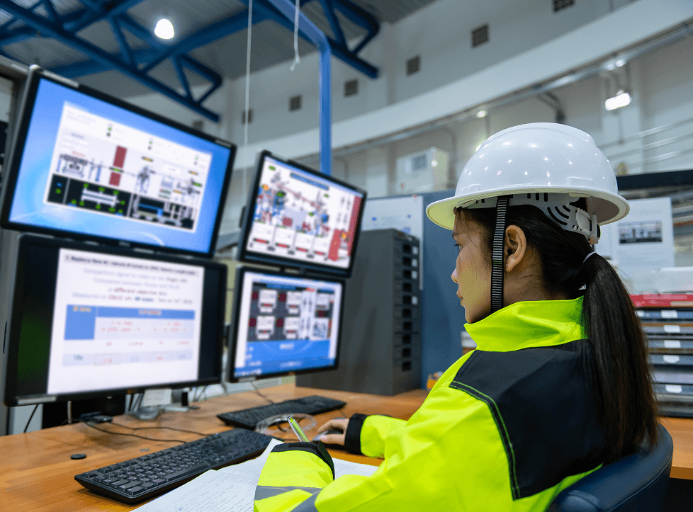 Image of a woman working on a computer with industrial dashboards on the screen in industrial environment